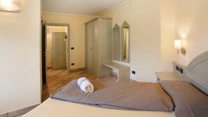 Een slaapkamer met een bed, nachtkastje, spiegel en een houten kledingkast.