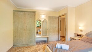 Une chambre à coucher avec un lit, une armoire en bois, un banc et une vue par la fenêtre.