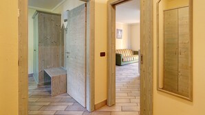 Un couloir avec des portes en bois menant à une pièce où se trouvent un banc et un canapé.