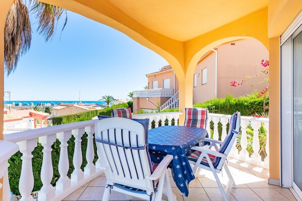 A balcony with a table and chairs, a view of the city, and a building with a balcony.