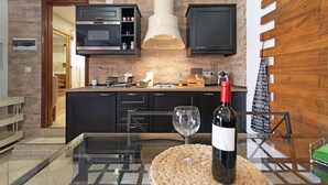 Une cuisine moderne avec des meubles de couleur sombre, un îlot central et une bouteille de vin posée sur la table.