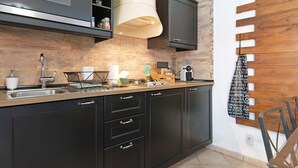 Une cuisine moderne avec des meubles de rangement aux couleurs sombres, un évier en acier inoxydable et un four encastré.