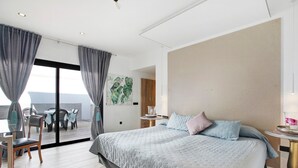 A hotel room with a large bed, a balcony with a table and chairs, and a view of the sea. - Villa Dolce Vita Tenerife Sur with Sea Views, Private Pool, Terraces, and Wi-Fi (Adeje)