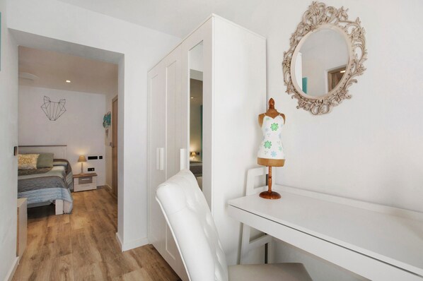 Un dormitorio con cama, mesita de noche, lámpara y un espejo en la pared.