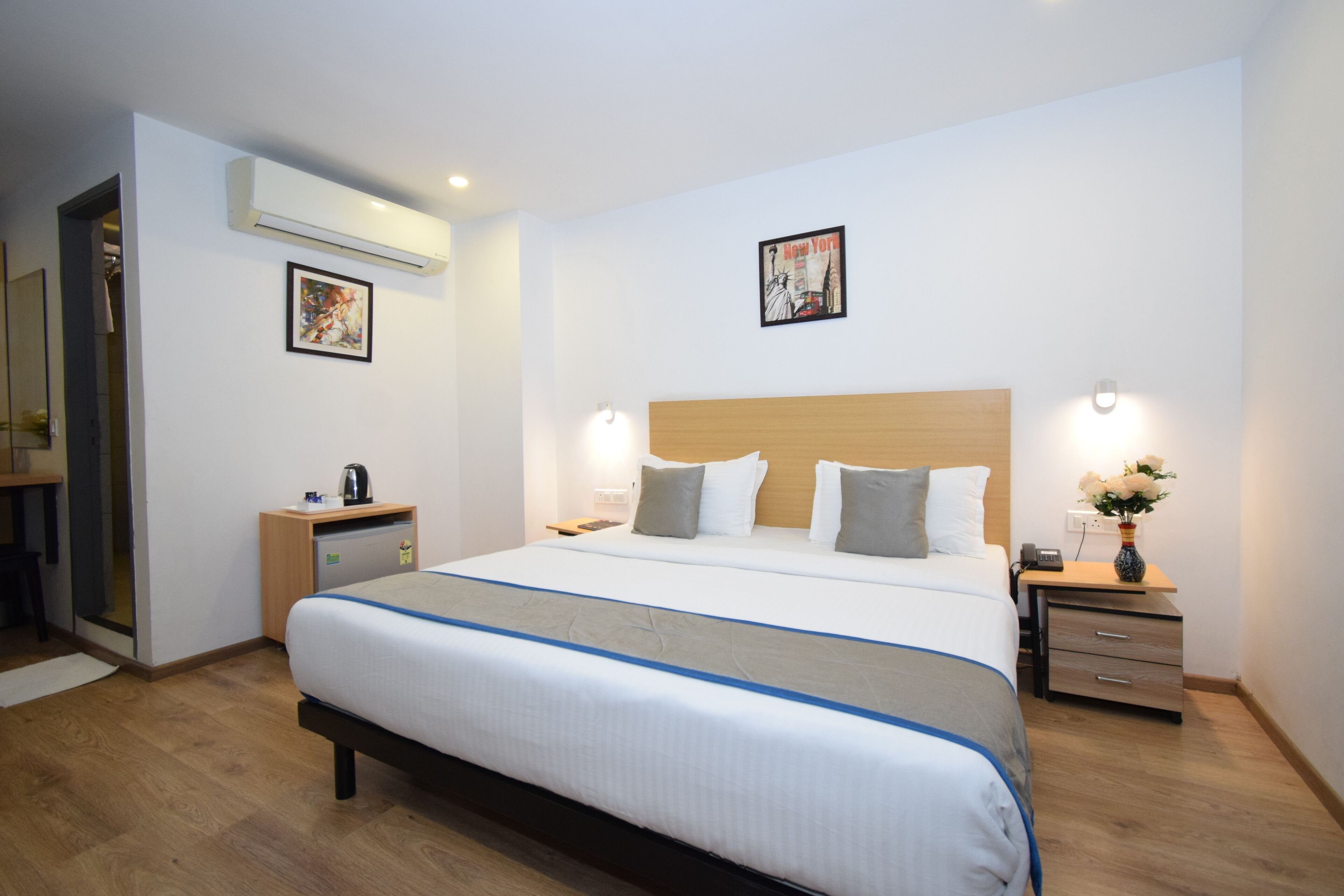 A hotel room with a large bed, bedside tables, a wardrobe, and a mirror.