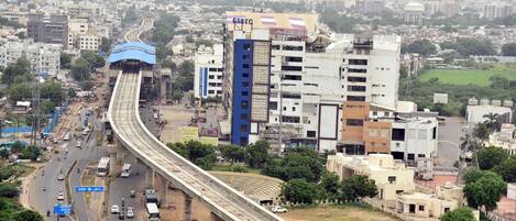 A busy urban area with a prominent elevated highway, various buildings, and a mix of vehicles and pedestrians.