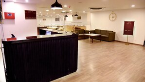 A modern hotel lobby with a reception desk, seating area, and a clock on the wall. - Ginger Ahmedabad RTO Circle (Ahmedabad)