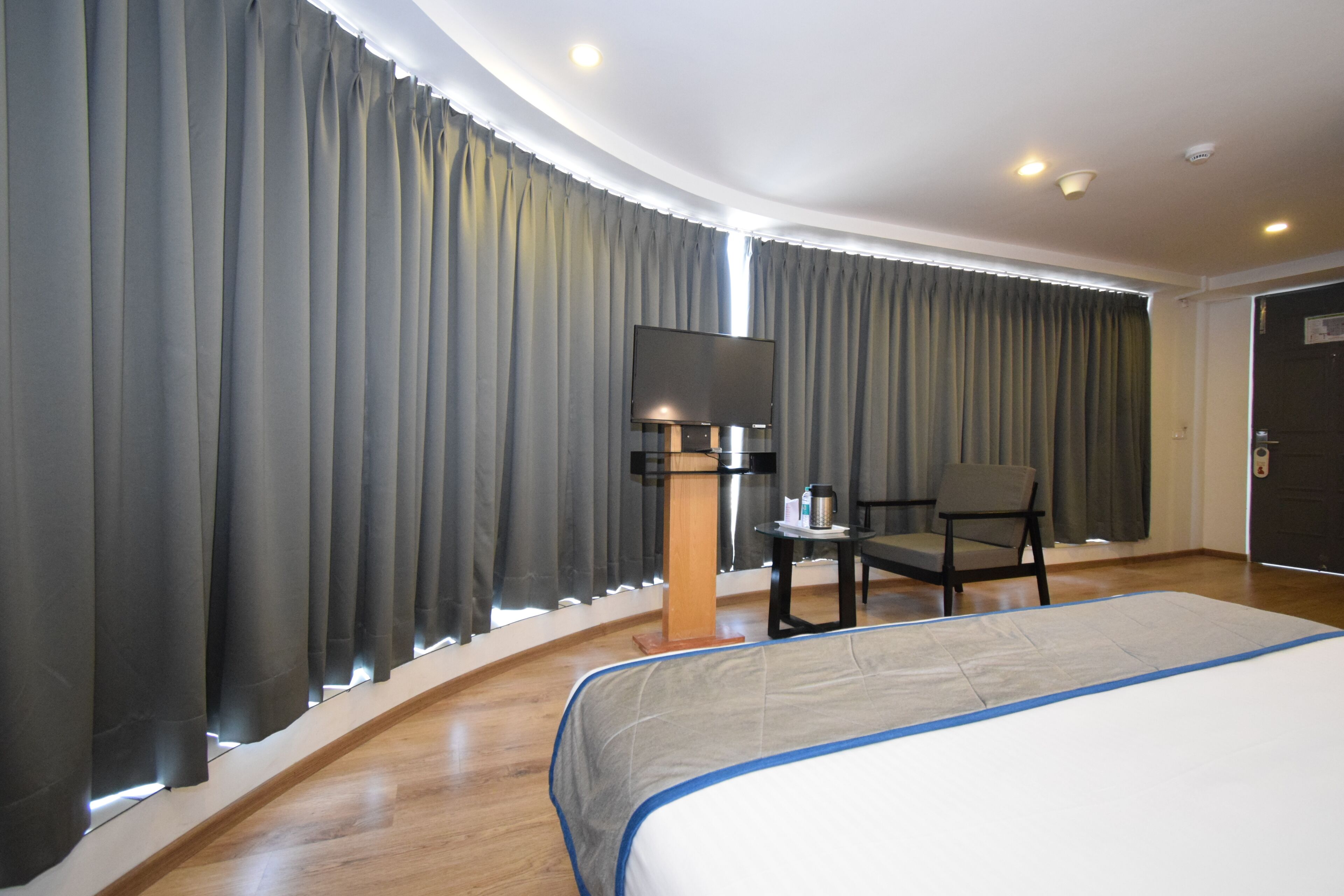 A hotel room with a large bed, a desk with a chair, a flat-screen TV, and a coffee maker.