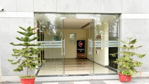 A hotel entrance with glass doors, a sign for the Central Inn, and two potted plants on either side. - Ginger Ahmedabad RTO Circle (Ahmedabad)