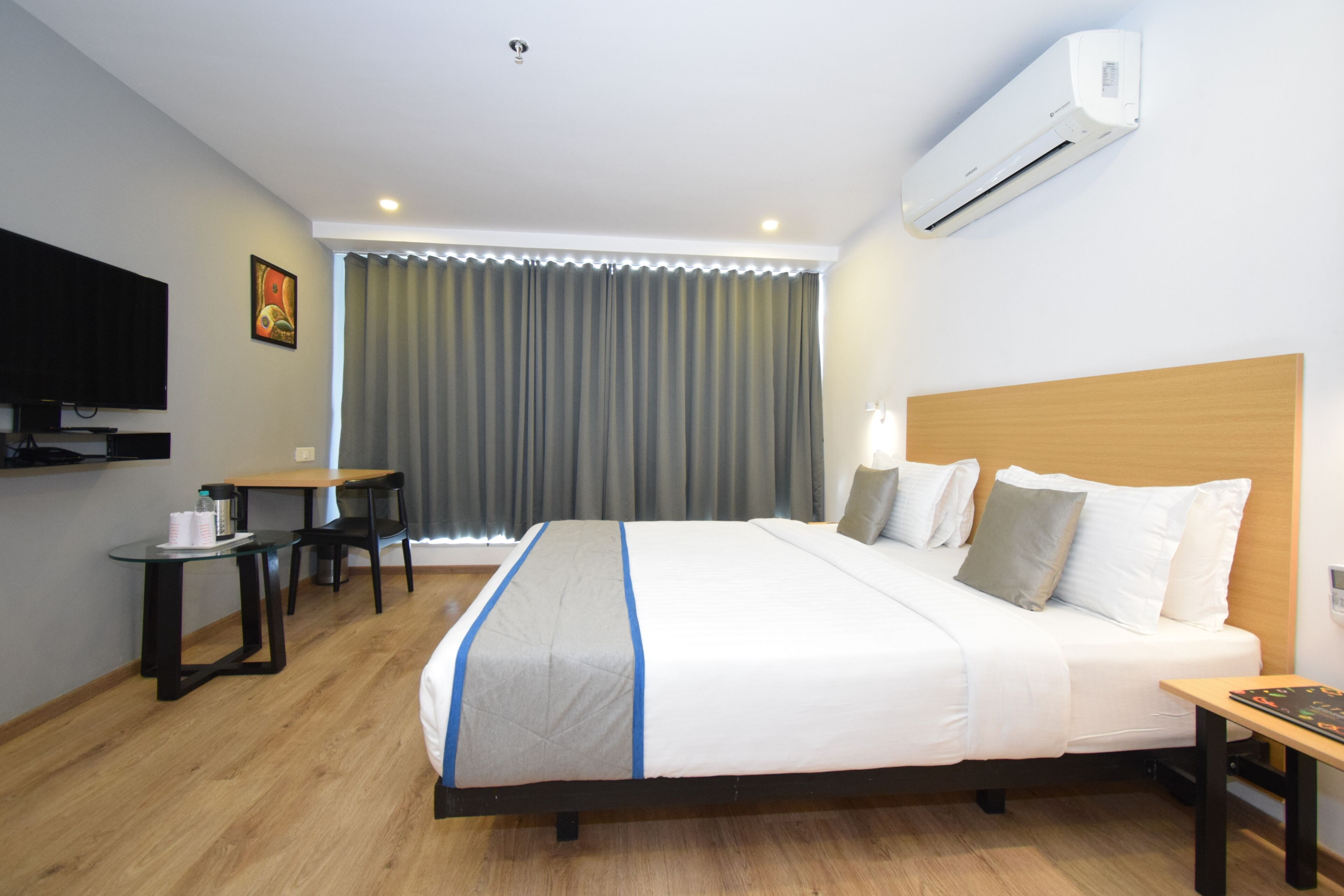 Ein Hotelzimmer mit Bett, Schreibtisch, Stuhl, Fernseher und Klimaanlage.