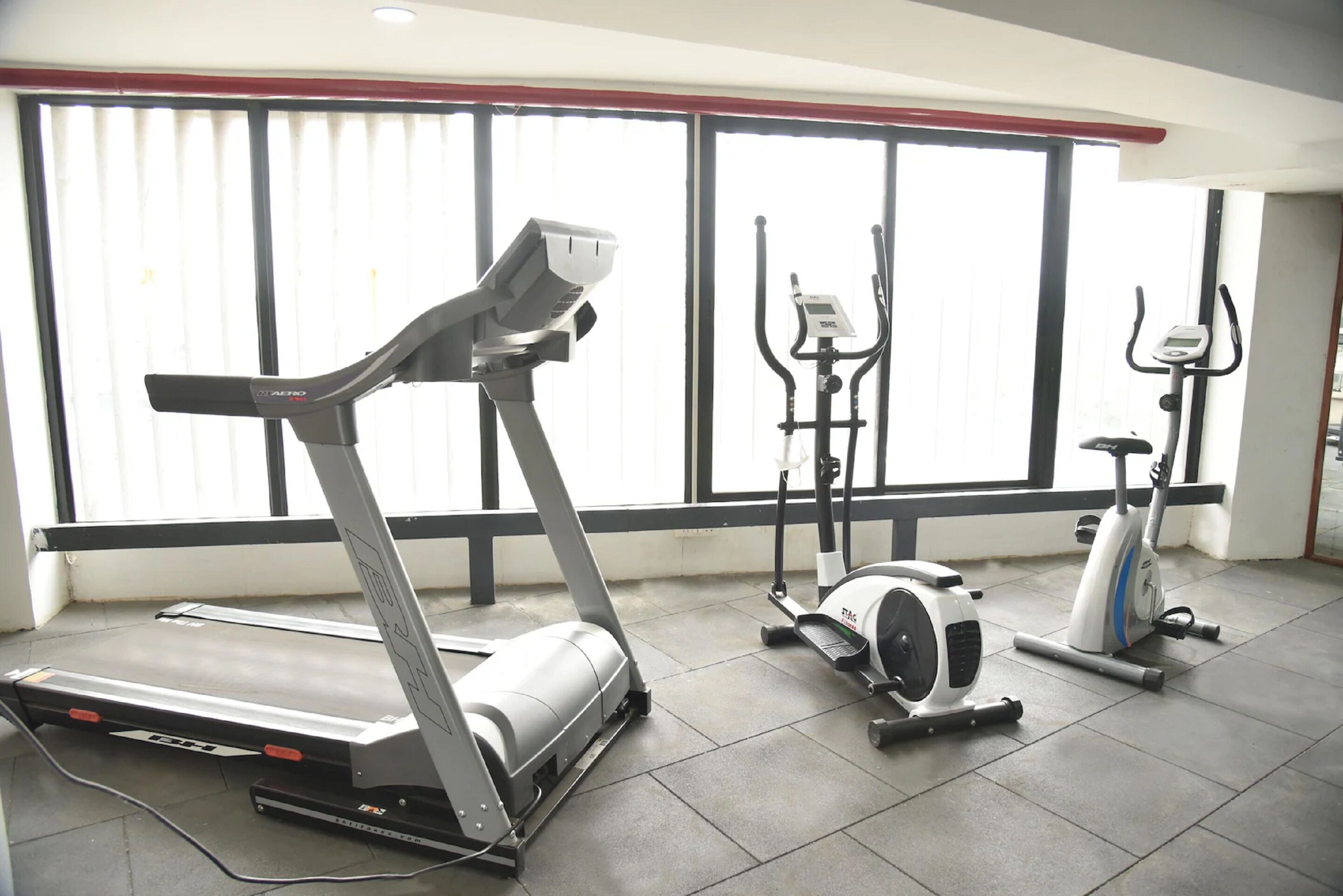 Un gimnasio con caminadora, elíptica y bicicletas estáticas.