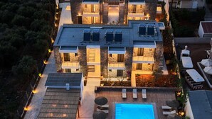 A modern hotel with a rooftop pool, outdoor seating, and a well-lit courtyard.