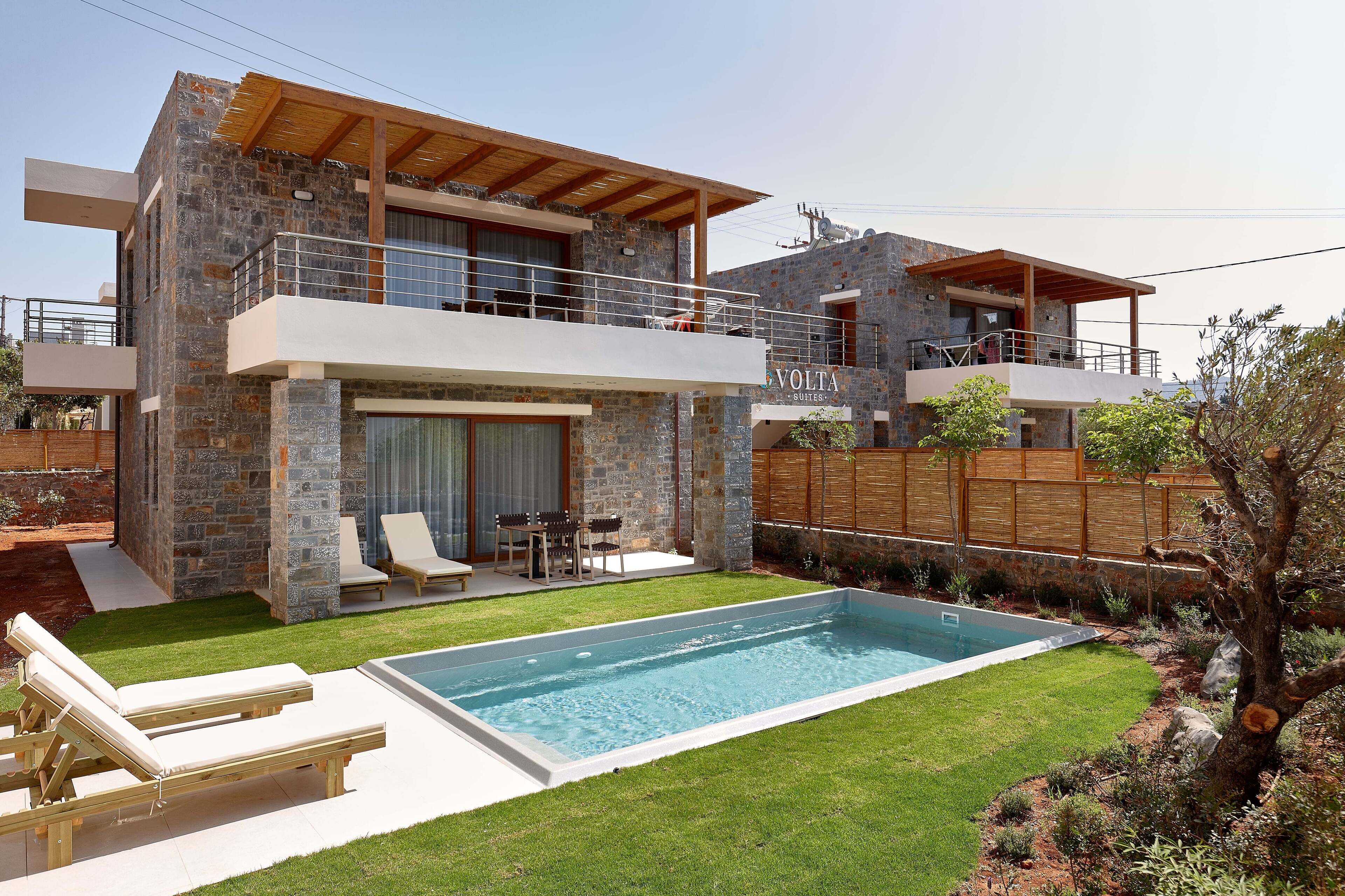 A modern two-story house with a stone facade, a swimming pool, and a wooden deck.