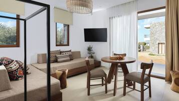 Ein modernes Wohnzimmer mit einer Couch, Sesseln, einem Esstisch und einem an der Wand montierten Fernseher.