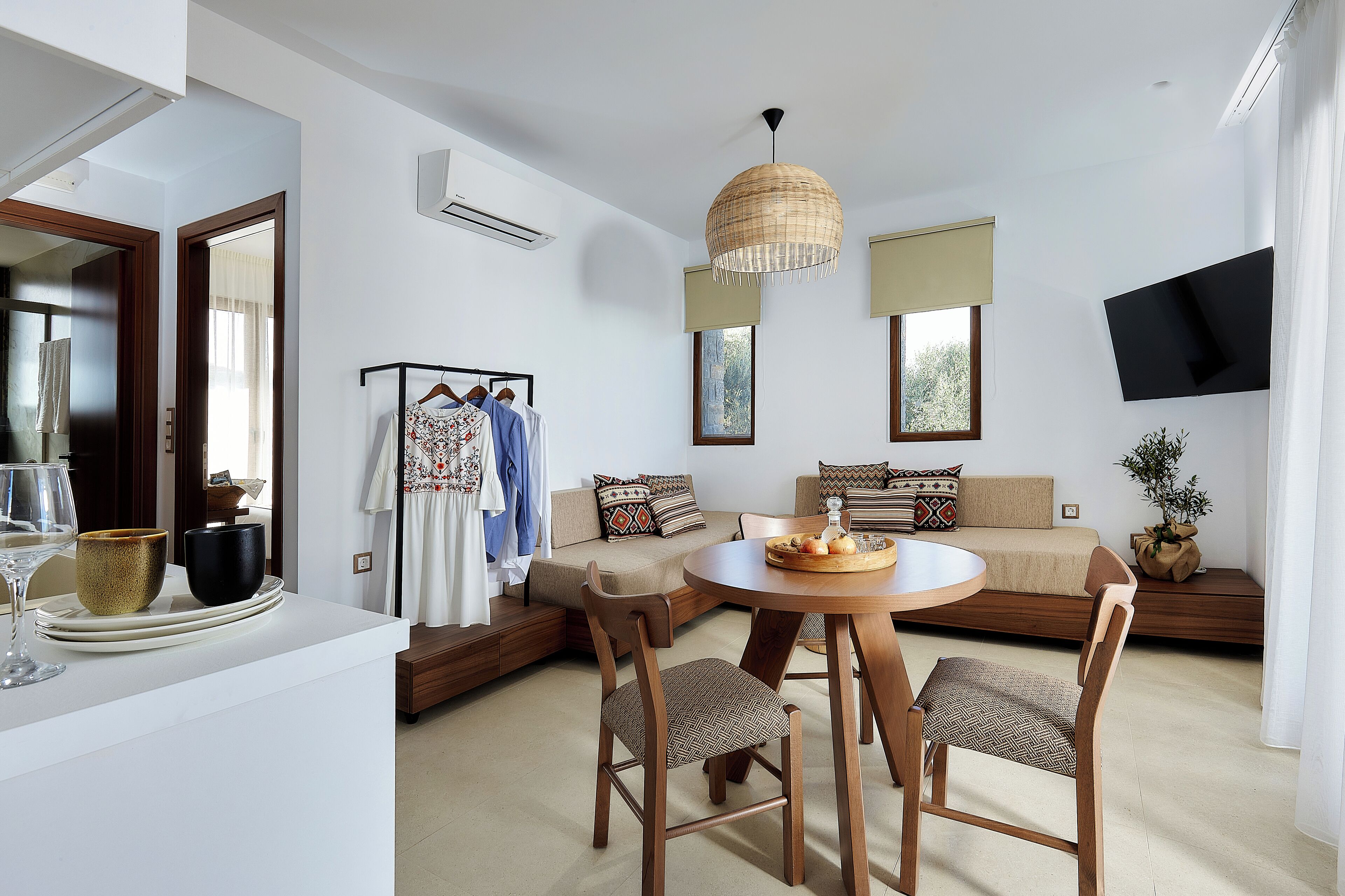 Una sala de estar moderna con sofá, mesa de comedor, sillas y una lámpara colgante.