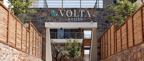 Een ingang naar Volta Suites, met stenen muren en een houten hek.