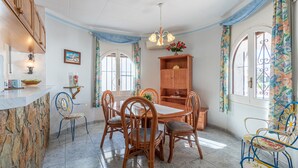 A dining area with a stone counter, wooden chairs, a wooden table, and a chandelier. - 0038-CREUS  House at the canal with pool and mooring (Empuriabrava)