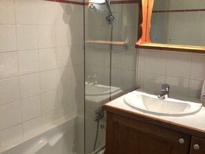A bathroom with a glass-enclosed shower, a white sink, and a wooden vanity. - Charming Chalet-Style Apartment with Terrace and Peaceful Setting, Close to Slopes and Amenities (Les Menuires)