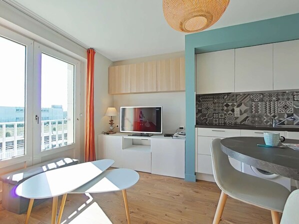 A modern kitchen with a TV, dining table, and chairs. - Renovated 2-room apartment, 4 pers, 1000m from the beach (Saint-Gilles-Croix-de-Vie)