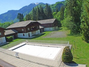 A residential building with a flat roof, a covered patio area, and a well-maintained lawn.