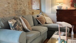 A cozy living room with a stone wall, a grey sofa, a wooden cabinet, and a glass coffee table. - THE CHICKEN COOP GUESTS HOUSE (Panicale)