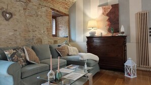 A cozy living room with a stone wall, a wooden cabinet, and a glass coffee table. - THE CHICKEN COOP GUESTS HOUSE (Panicale)
