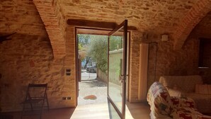 A room with a sloped ceiling, a wooden ladder, a bed, and a door leading outside. - THE CHICKEN COOP GUESTS HOUSE (Panicale)