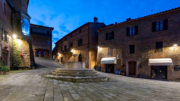 A historic street with stone buildings, a central fountain, and outdoor seating areas. - THE CHICKEN COOP GUESTS HOUSE (Panicale)
