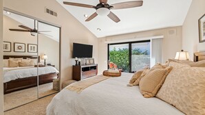 A bedroom with a large bed, a ceiling fan, a TV, and a view of greenery outside. - PGA West 3Bed Golf Mountain and Course View Home (La Quinta)