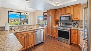 A modern kitchen with granite countertops, stainless steel appliances, and wooden cabinetry. - PGA West 3Bed Golf Mountain and Course View Home (La Quinta)