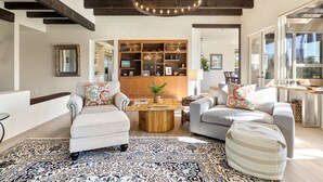 A spacious living room with a large wooden coffee table, two sofas, a patterned rug, and a built-in bookshelf.