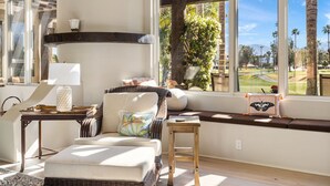 A cozy room with a wicker sofa, a small table with a lamp, and a bench with a butterfly pillow.