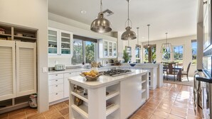 A modern kitchen with white cabinetry, a central island, and pendant lighting.