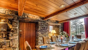 Un coin repas rustique avec un mur en pierre, un plafond en bois et une statue de Bouddha.
