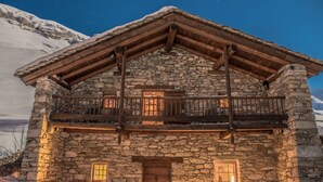 Un bâtiment en pierre doté d’un balcon en bois et d’une porte en bois.