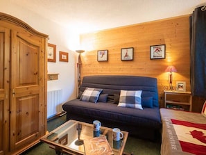 Ein gemütliches Zimmer mit einem dunkelblauen Sofa, einem Holzschrank und einem Glastisch mit einem Buch und zwei Tassen.