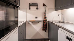 Uma cozinha compacta com forno embutido, lava-louças e pia.