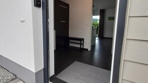 Una entrada moderna con puerta corredera de vidrio, un banco y vistas del interior.