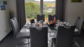 Comedor con una mesa preparada para cuatro, con vistas a un paisaje pintoresco.