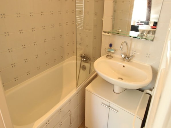 A bathroom with a bathtub, a sink, and a glass shower enclosure.