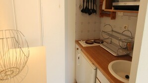 A compact kitchen with white cabinets, a wooden countertop, a sink, and a microwave.