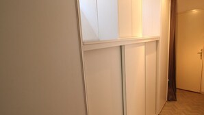 A hallway with a wooden herringbone floor, white walls, and a closed door at the end.