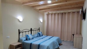 A bedroom with a bed, a nightstand, a wooden bench, and a TV mounted on the wall. - Hotel Novo (Ponferrada)