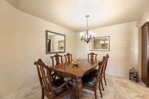 A dining room with a wooden table, six chairs, a chandelier, and two wall-mounted mirrors. - **NEW** Beautiful Racquet Club Condo (Scottsdale)