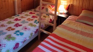 Habitación con literas, una mesita con lámpara y una colcha estampada con motivos florales.