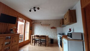 Una cocina con armarios de madera, una pared de piedra, una mesa de comedor con sillas y un horno empotrado.