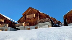 Una cabaña de madera con balcón, al pie de un cielo azul despejado.