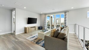 A modern living room with a flat-screen TV, a sofa, a coffee table, and a view of the outside.