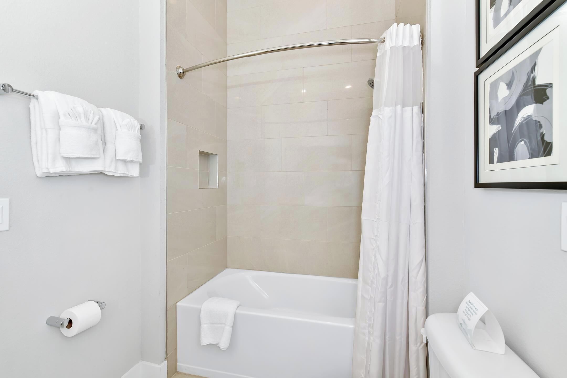 Une salle de bain moderne avec une douche à parois de verre, une baignoire blanche et des toilettes dotées d’un porte-serviettes.