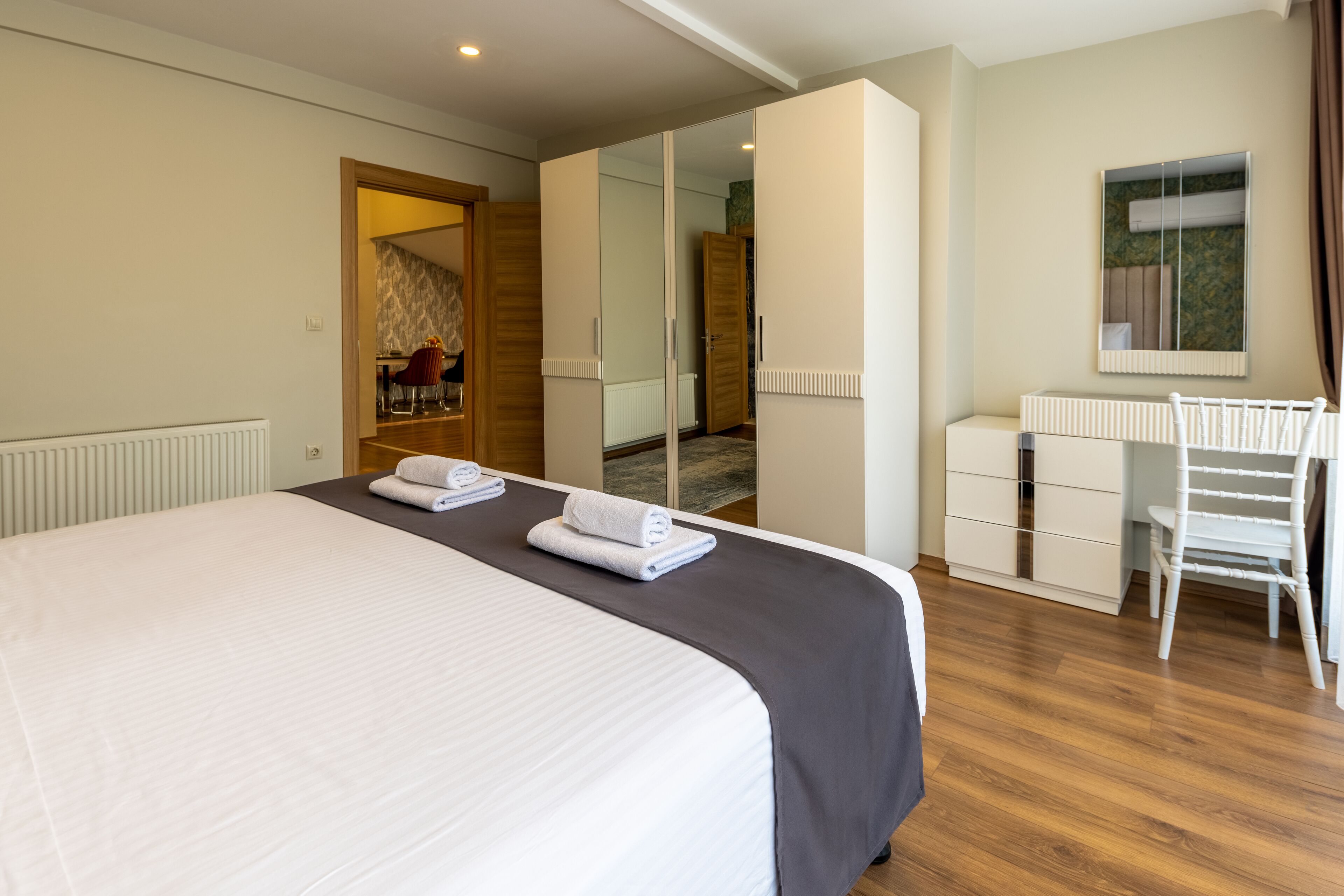 A hotel room with a large bed, a desk, a chair, and a mirror.